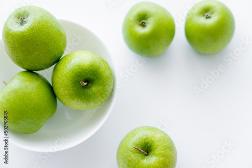 top view of juicy and ripe apples in bowl on white.