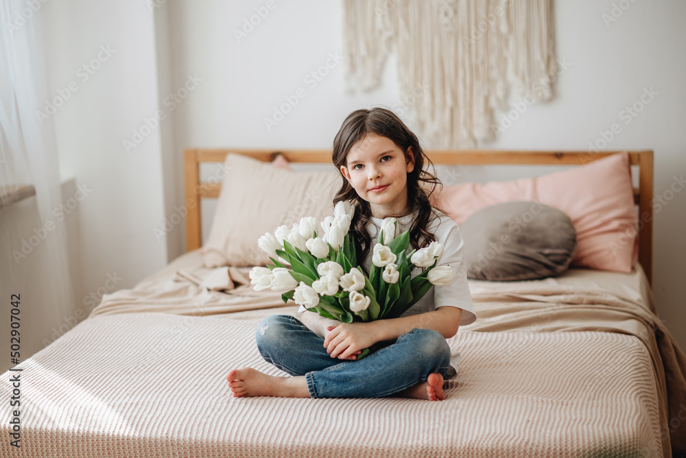 A girl in a white T-shirt with a bouquet of flowers. A girl with a smile has white tulips. A girl in a white T-shirt with a bouquet of flowers. A girl with a smile has white tulips.