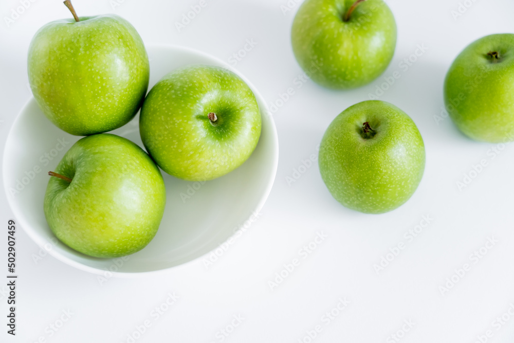 top view of green apples in bowl on white. top view of green apples in bowl on white.