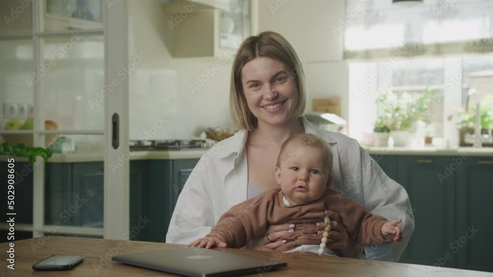 Young adult caucasian mother interacting with her son in front of her laptop Young adult caucasian mother interacting with her son in front of her laptop