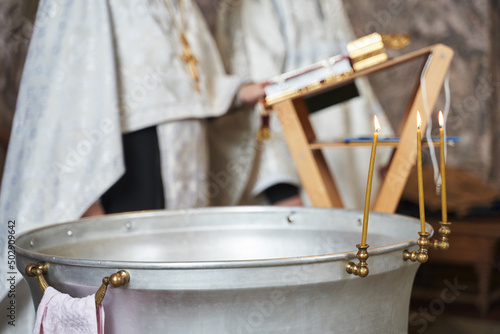 Canvastavla baptismal cup with burning candles in an orthodox church in front of an orthodox priest