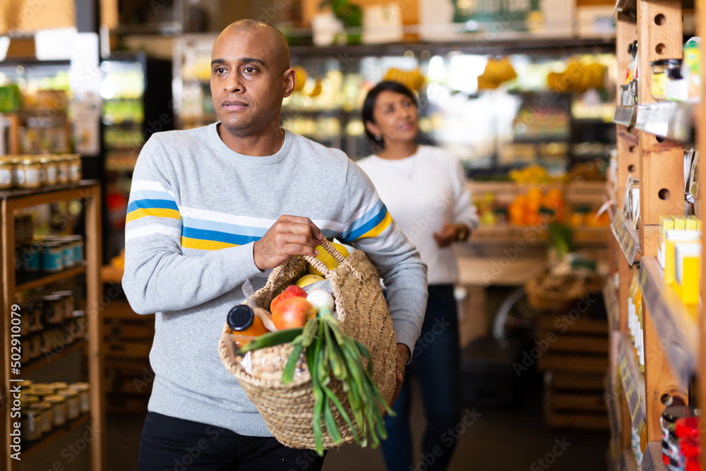 Portrait of man with bag full of groceries in supermarket interior