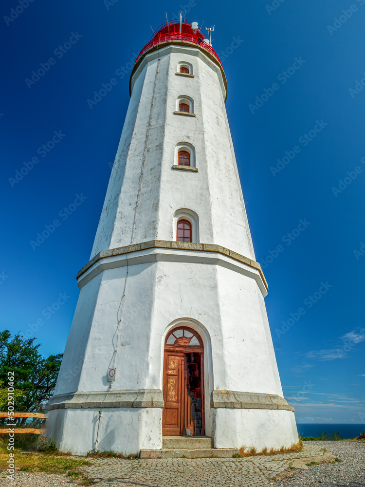 The Hiddensee Light House with the name Dornbusch is surrounded from green nature and blue sky background 