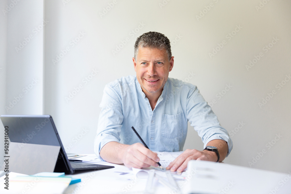 Business portrait of architect sitting at his work table and planning in his modern bright office Business portrait of architect sitting at his work table and planning in his modern bright office