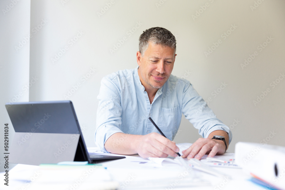 Business portrait of architect sitting at his work table and planning in his modern bright office Business portrait of architect sitting at his work table and planning in his modern bright office