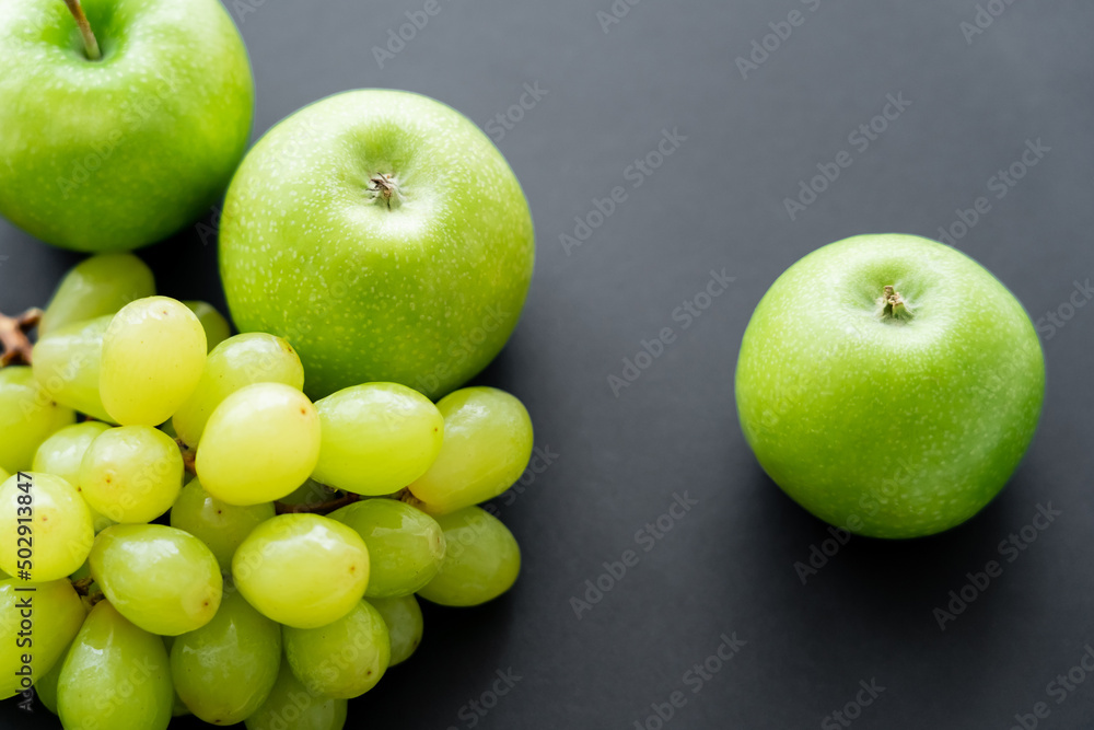 top view of tasty apples near green grapes on black. top view of tasty apples near green grapes on black.