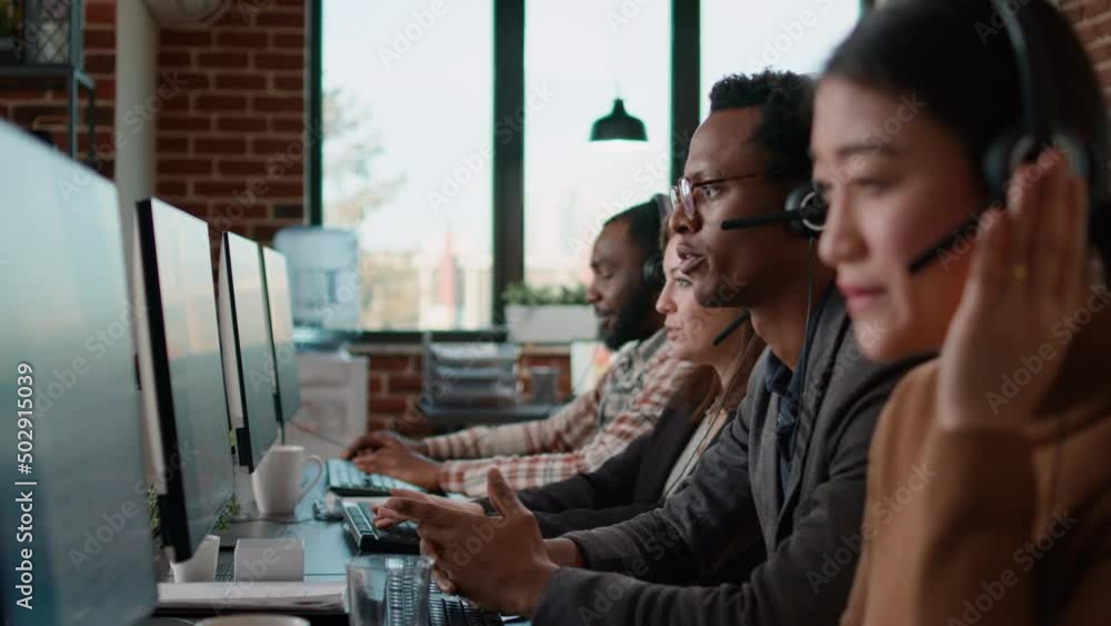 Helpline agents talking to clients on headset at call center job, using computer to have remote conversation. People working at customer service care helping with telemarketing communication.