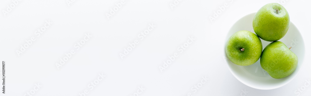 top view of green apples in bowl on white, banner. top view of green apples in bowl on white, banner.