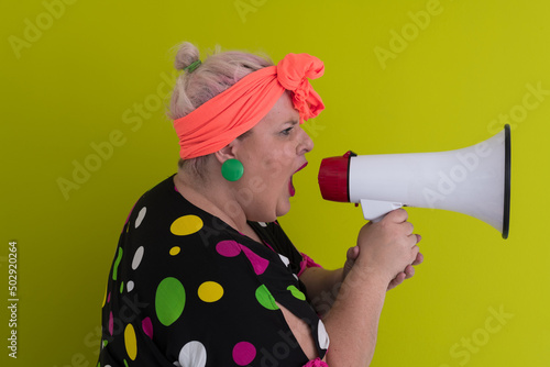 Funny plus size woman woman posing isolated on pastel green background studio portrait. People emotions lifestyle concept. Mock up copy space. Screaming in megaphone. 