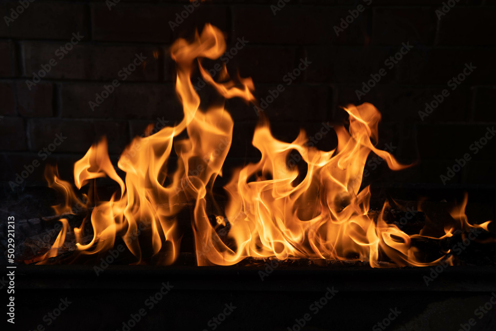 Fototapeta premium The texture of the fire is close, red and yellow, thermal energy at the fuel supply point at night, lights on a black background.