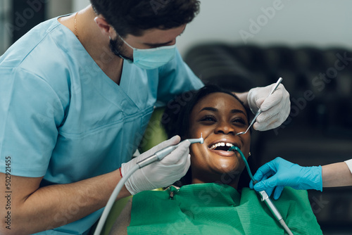 Dentist providing dental care treatment to a african american female patient