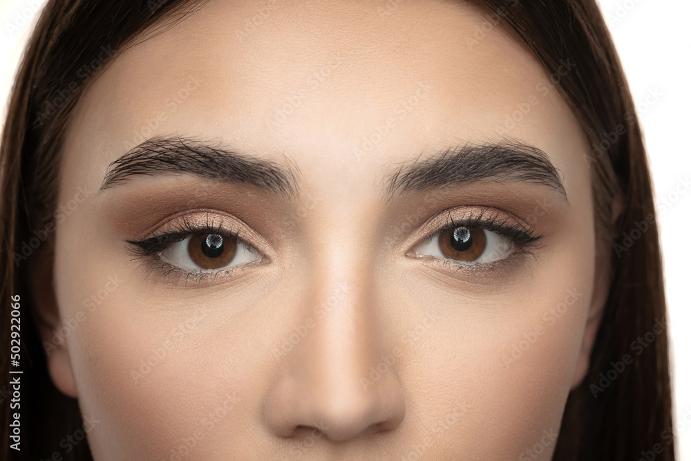 Cropped beautiful female face with nude makeup isolated over white studio background. Brown eyes beauty Cropped beautiful female face with nude makeup isolated over white studio background. Brown eyes beauty