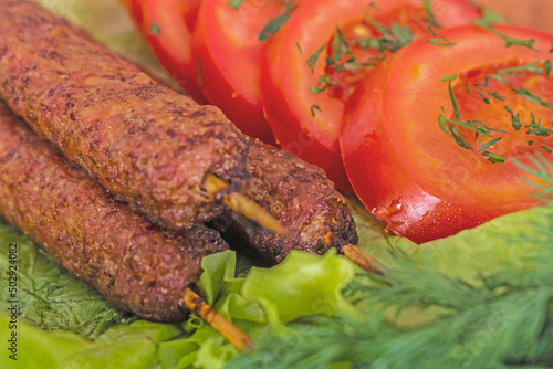 barbecue meat and vegetables lie on green lettuce leaves