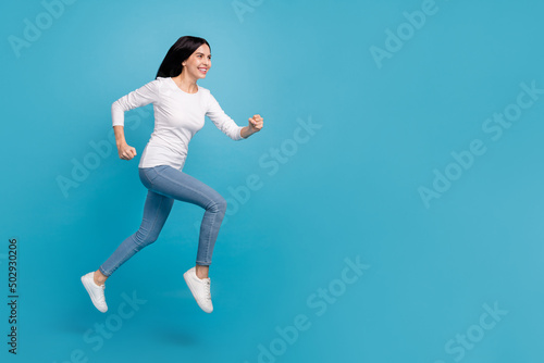 Full length body size view of attractive cheerful sportive active girl jumping running isolated on bright blue color background