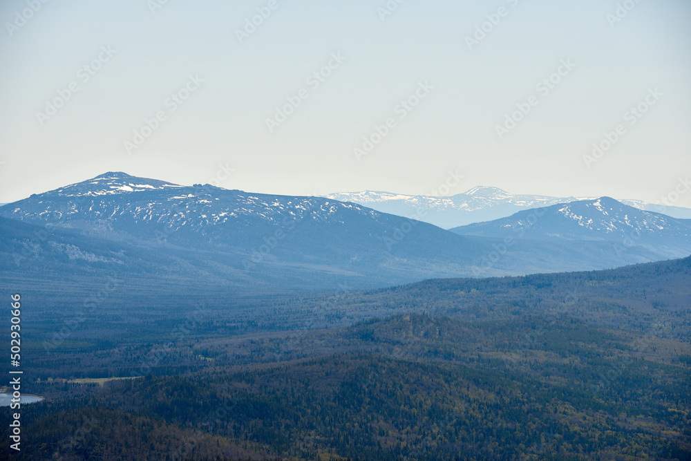 Picturesque aerial shot of vast wild woodland and high mountains with snow-capped peaks. National park, the Urals, Russia Picturesque aerial shot of vast wild woodland and high mountains with snow-capped peaks. National park, the Urals, Russia