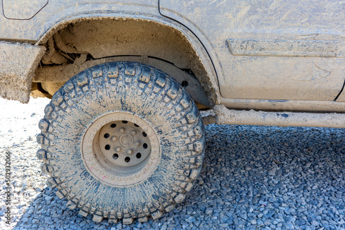 The wheel and part of the car are completely covered with mud.