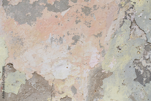 Old flaky wall with destroyed plaster. Renovation of old house. Industrial style design wall background. Grunge cracked concrete wall with old paint. Shabby peeling old background