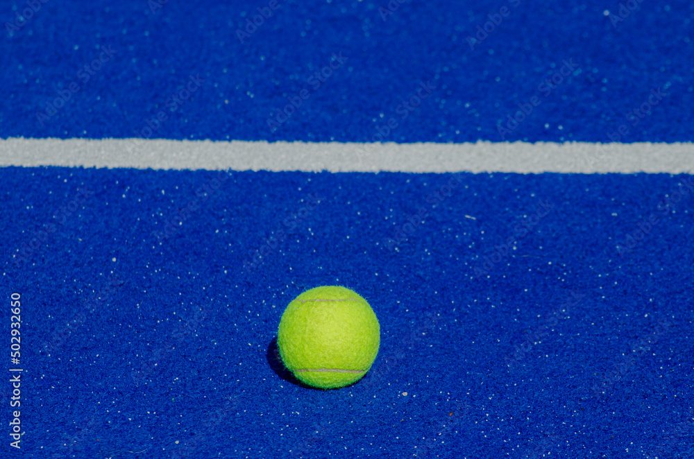 blue paddle tennis court, a solitary ball close to the baseline