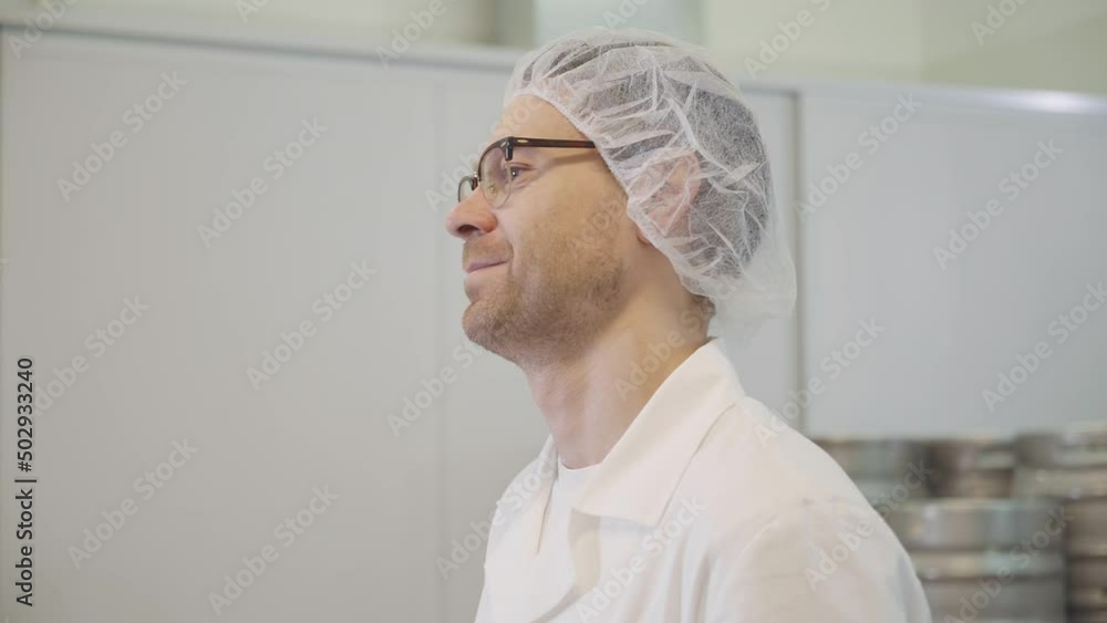 Close-up of a male worker at the industrial brewery facility. Worker is wearing sterile clothes in the brewery production room. Worker is producing alcoholic beverages at the brewery plant. Close-up of a male worker at the industrial brewery facility. Worker is wearing sterile clothes in the brewery production room. Worker is producing alcoholic beverages at the brewery plant.