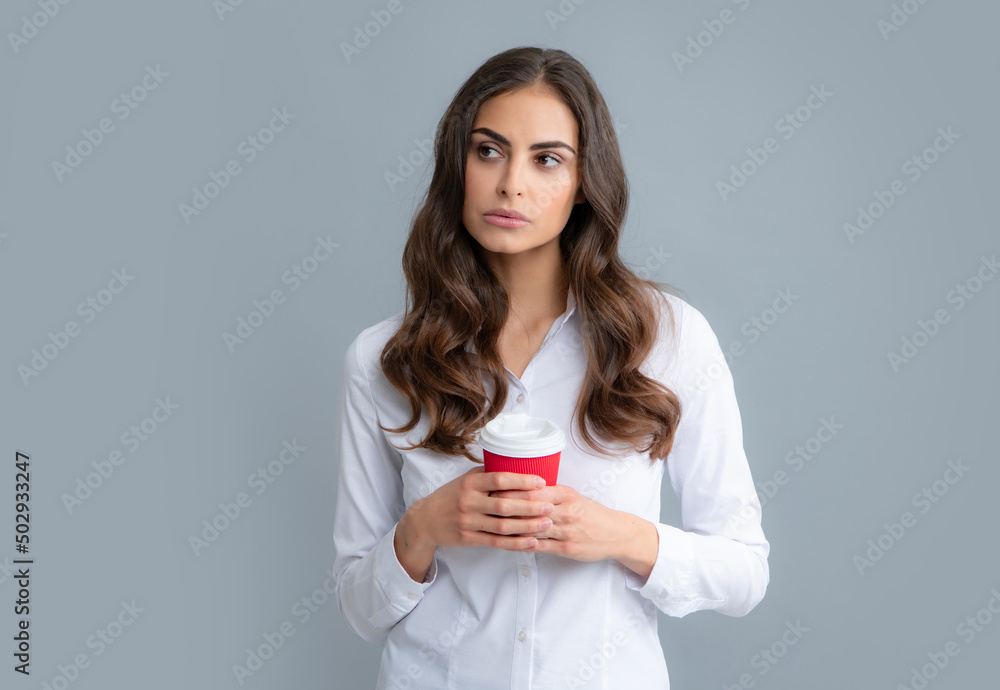 Portrait of nice cute girl holding cup of coffee. Young woman smiling with a coffee cup, isolated on gray background. Portrait of nice cute girl holding cup of coffee. Young woman smiling with a coffee cup, isolated on gray background.