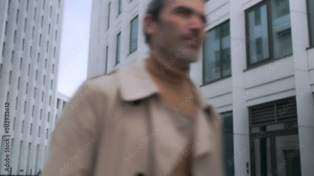Front view of an ambitious handsome businessman walking down a city street in the city center. Stylish confident business man walks forward to the camera, looks ahead. Front view of an ambitious handsome businessman walking down a city street in the city center. Stylish confident business man walks forward to the camera, looks ahead.