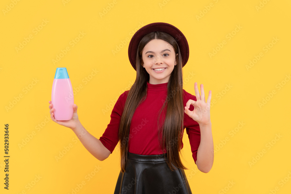 ok. happy girl in hat hold shampoo. presenting cosmetic product for teen. ok. happy girl in hat hold shampoo. presenting cosmetic product for teen.