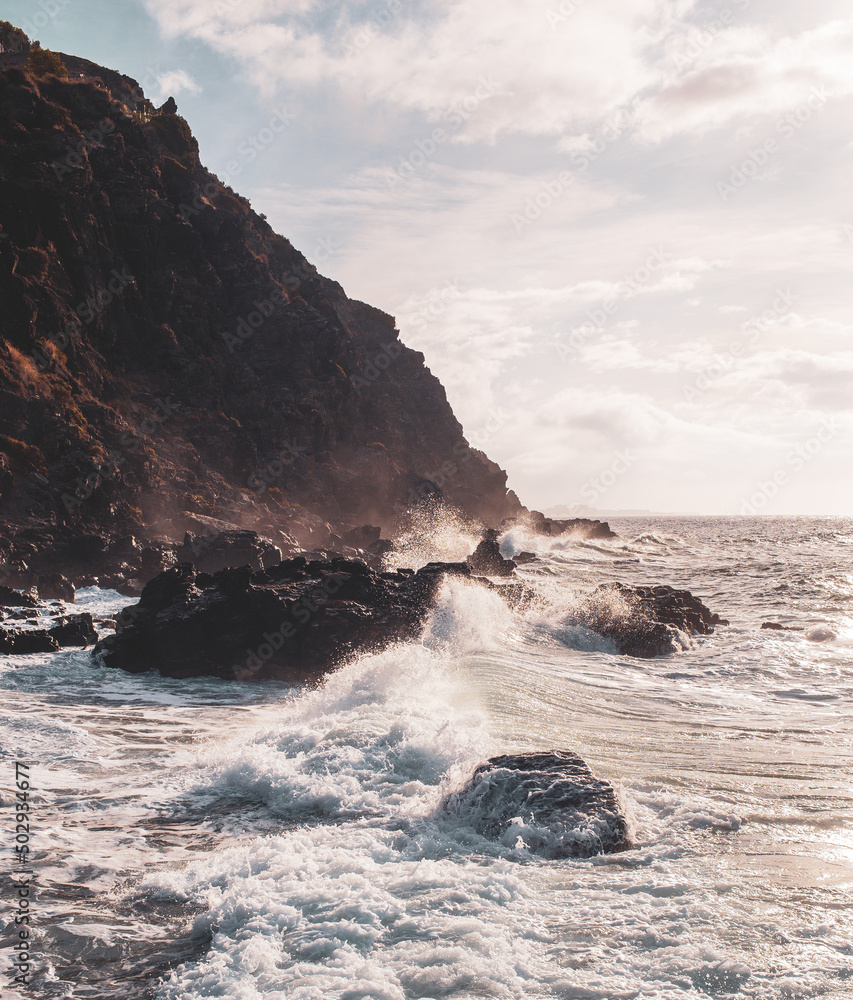 Obraz premium Stormy ocean sea water drops in cliffs and big waves come to the short in sunset or sunrise in blue and orange colors