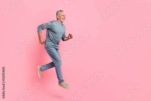 Full length body size view of attractive cheery grey-haired man jumping running copy space isolated over pink pastel color background