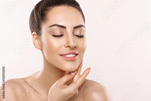 Beautiful Woman Face Skin Care. Portrait Of Attractive Young Female Applying Cream Cosmetics. Closeup Of Beauty Smiling Girl With Natural Makeup And Fresh Skin. Cosmetology. Dermatology. Spa. photo