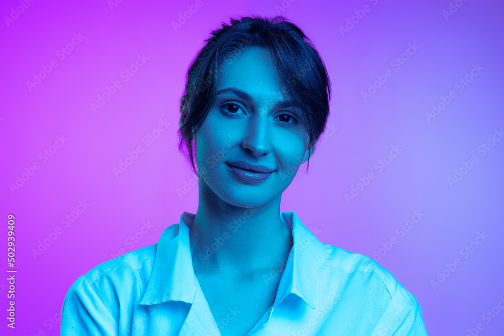 Young beautiful woman in white shirt isolated over purple studio background in neon light. Concept of emotions, facial expression, art, beauty Young beautiful woman in white shirt isolated over purple studio background in neon light. Concept of emotions, facial expression, art, beauty