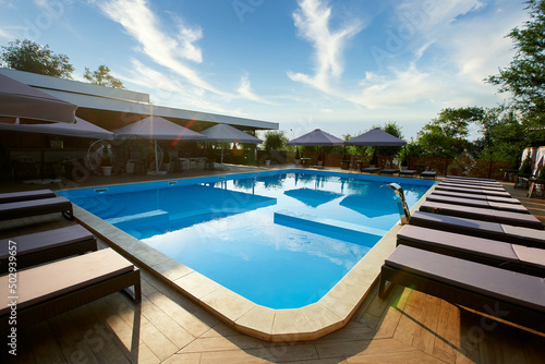 Swimming pool area with deck chairs and sun umbrellas along the poolside in luxury resort Fototapet