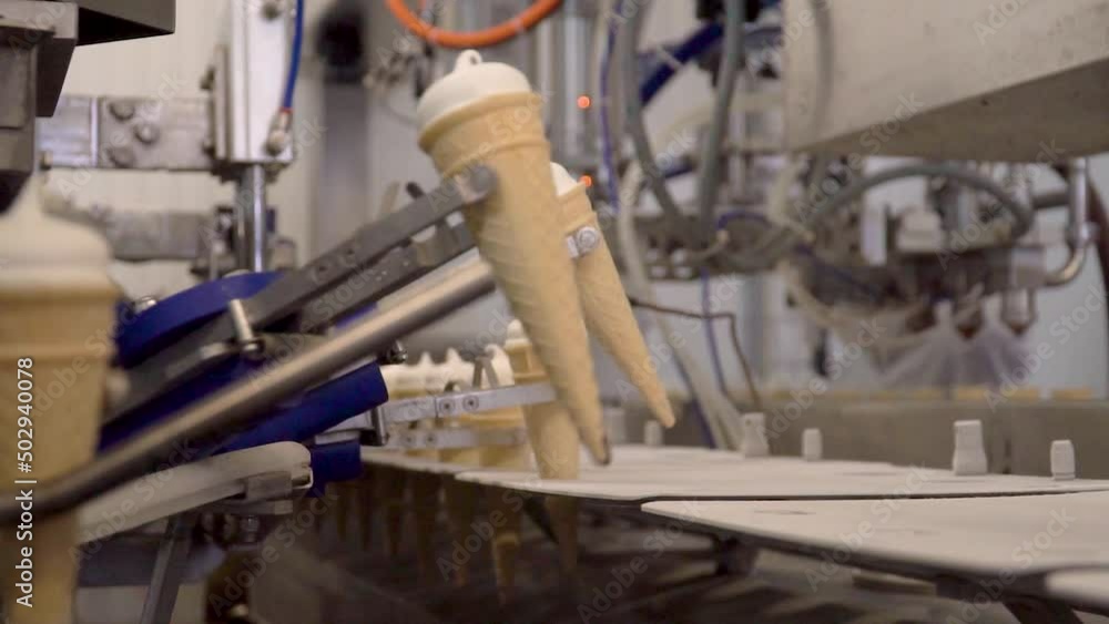 A Conveyor at the Ice-Cream Production. Waffle Cups Moving on the conveyor belt. Industrial Line. Factory Worker Puts the Desserts to the manufacturing Line. Modern Food Industry. Close Up A Conveyor at the Ice-Cream Production. Waffle Cups Moving on the conveyor belt. Industrial Line. Factory Worker Puts the Desserts to the manufacturing Line. Modern Food Industry. Close Up
