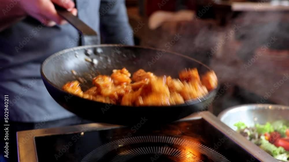 Slow motion of cook roasts chicken meat in sauce, tosses it in frying pan. Slow motion of cook roasts chicken meat in sauce, tosses it in frying pan.