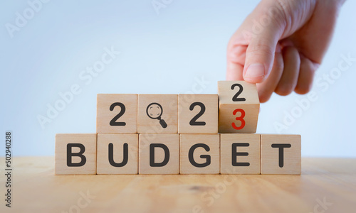 2023 Budget planning and allocation concept.  Hand flips wooden cube and changes the inscription "BUDGET 2022" to "BUDGET 2023" with white  background, copy space. Use for banner and presentation.