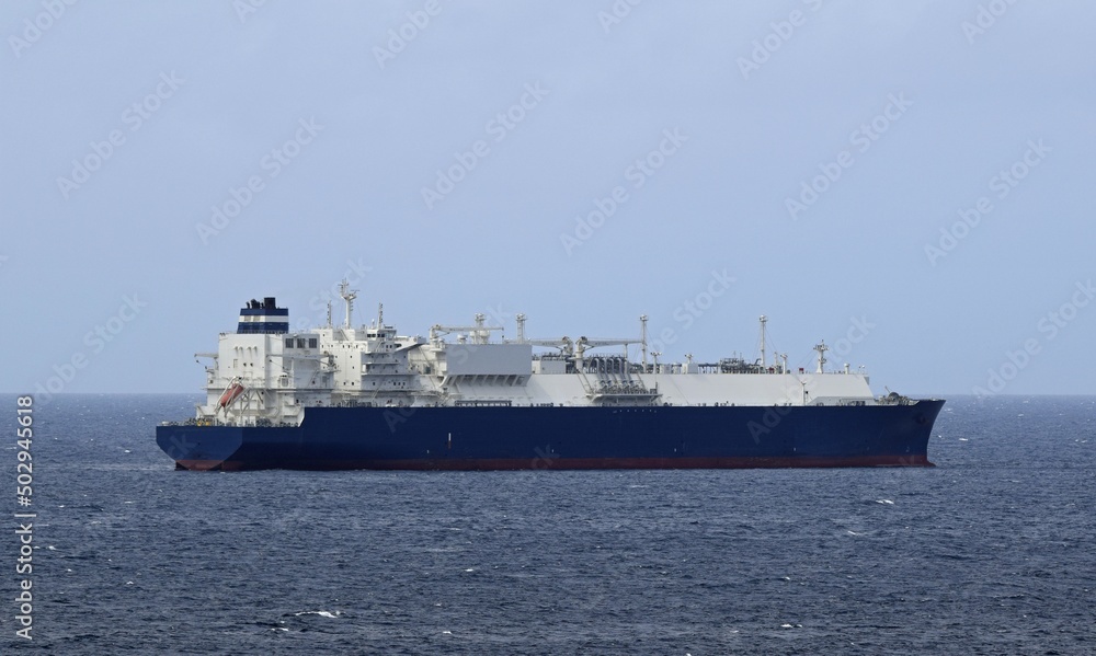 Large blue and white liquid gas Tanker ship in the ocean, blue sky in the background