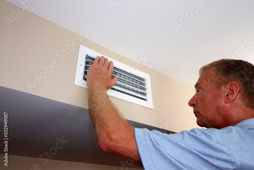 Left Hand of a Mature Man Placed on an Air Vent in a Home on a Wall