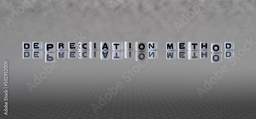 depreciation method word or concept represented by black and white letter cubes on a grey horizon background stretching to infinity photo