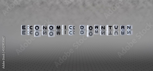 economic downturn word or concept represented by black and white letter cubes on a grey horizon background stretching to infinity