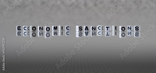 economic sanctions word or concept represented by black and white letter cubes on a grey horizon background stretching to infinity