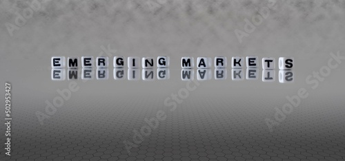 emerging markets word or concept represented by black and white letter cubes on a grey horizon background stretching to infinity