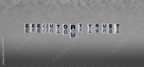 executory trust word or concept represented by black and white letter cubes on a grey horizon background stretching to infinity
