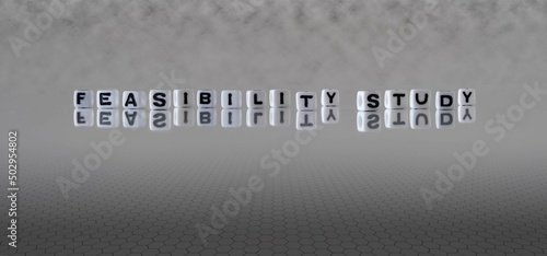 feasibility study word or concept represented by black and white letter cubes on a grey horizon background stretching to infinity