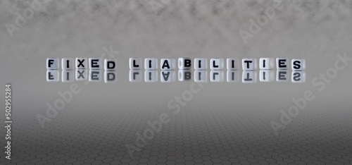 fixed liabilities word or concept represented by black and white letter cubes on a grey horizon background stretching to infinity