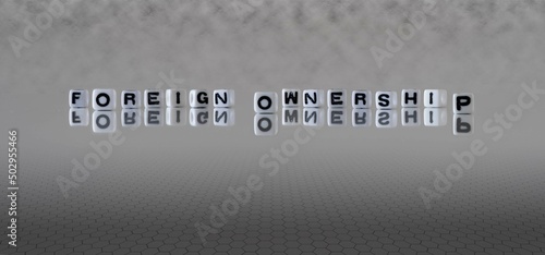 foreign ownership word or concept represented by black and white letter cubes on a grey horizon background stretching to infinity