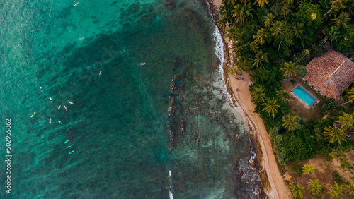 View of the ocean and coast from a drone, surfers with boards in the water waiting for the waves,