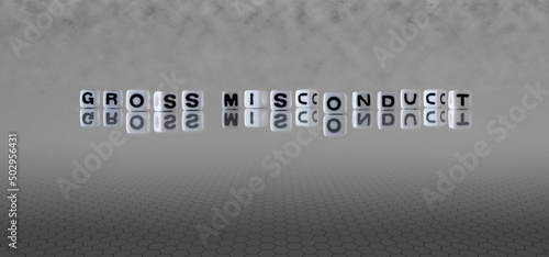 gross misconduct word or concept represented by black and white letter cubes on a grey horizon background stretching to infinity photo