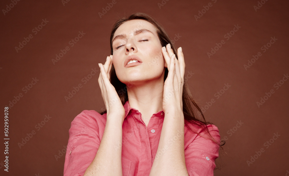 Below view of attractive young woman with closed massaging temples against brown background Below view of attractive young woman with closed massaging temples against brown background