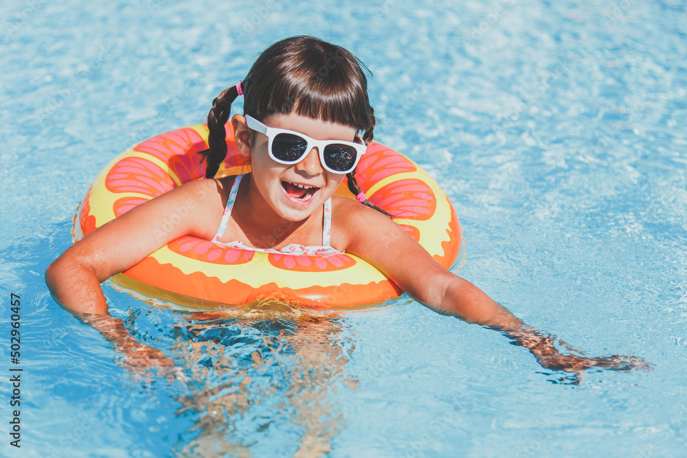 close-up portrait of a toddler girl 4 years old swims in the pool in the summer in an inflatable circle, vacation concept