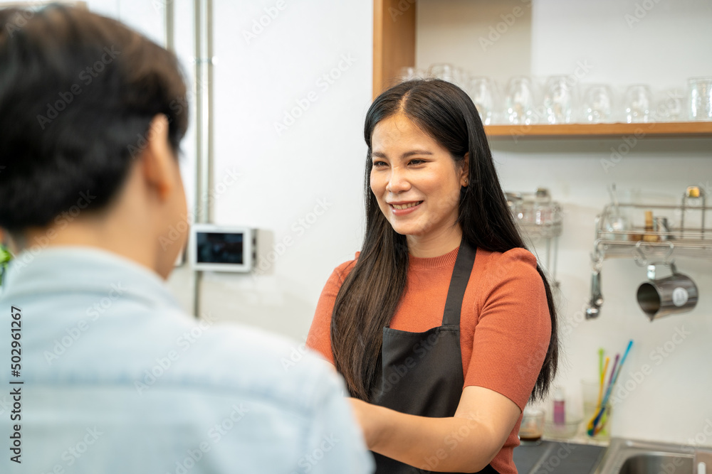 Barista in apron serving customers in coffee shop,Serving customer over the counter.