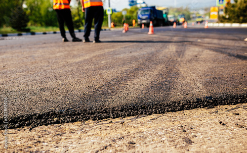 A large layer of fresh hot asphalt. Road construction. Construction of a new road